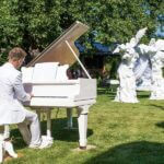 Pianist In All White Plays A White Piano Outdoors Near White Sculptures At A Cocktail Hour In NYC