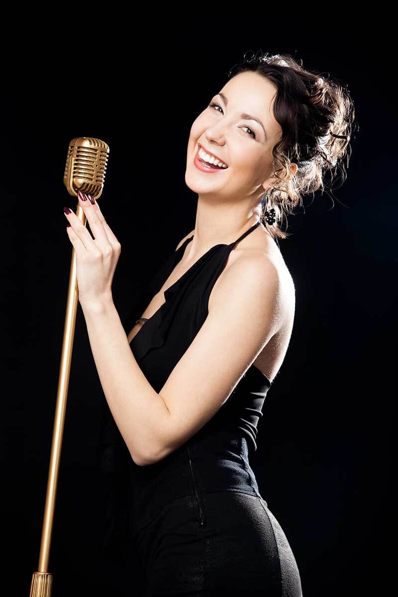 Attractive Young Female Wedding Singer In Formal Dress Smiling At Camera Holding Microphone On A Mic Stand