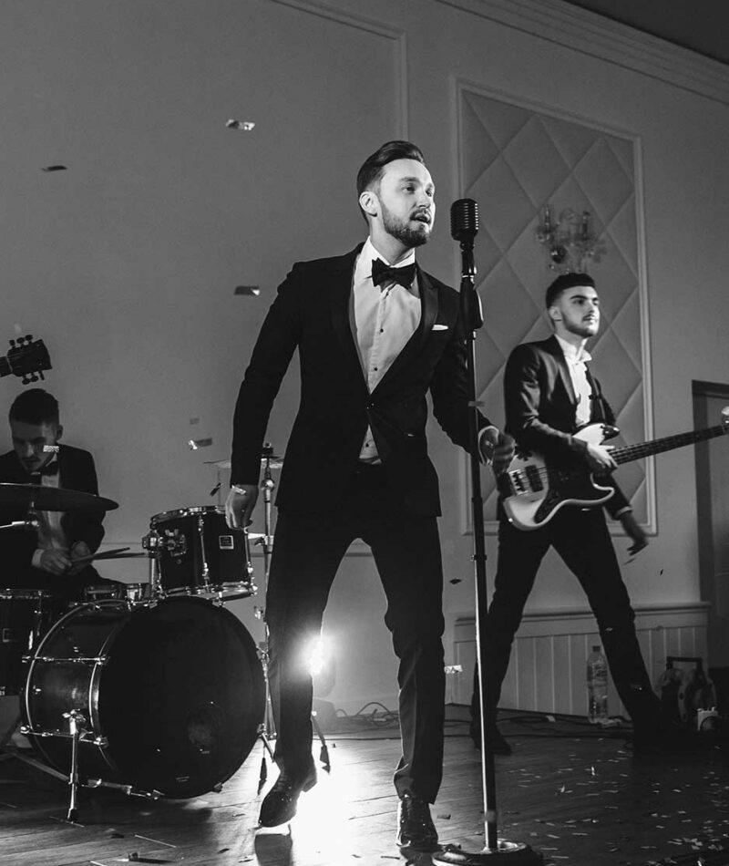 Male Wedding Singer In Suit Performing Live With Rock Band