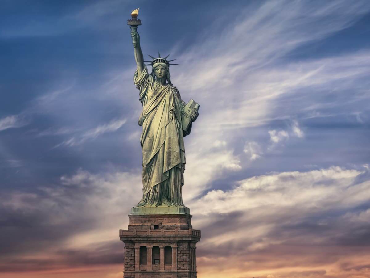 Statue Of Liberty, Manhattan NYC - Colorful frontal image of the statue of liberty against a cloudy blue sky.