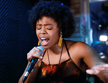 young black woman singing into microphone