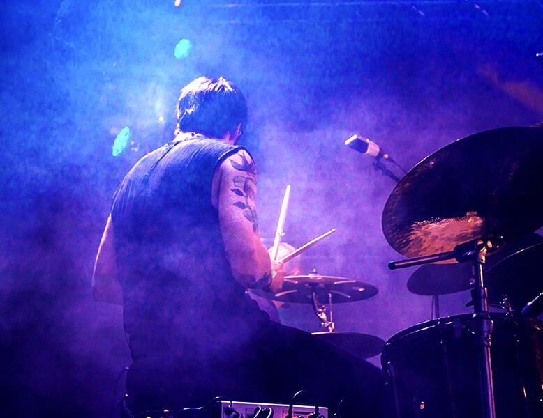 Tattoo'd rock / metal drummer surrounded by stage fog at his drum kit on stage at the bat mitzvah celebration